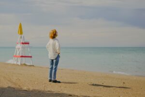 Mom, sanding on the beach next to a life-guard tower with a shadow that has no source.