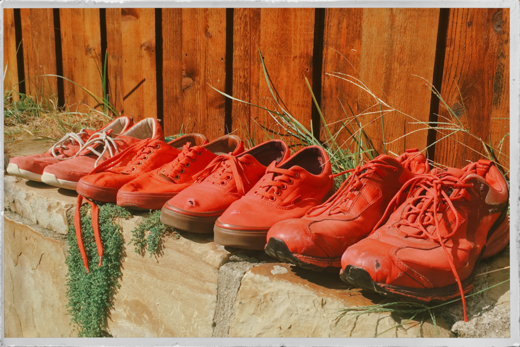 4 pairs of Red Shoes in row on a stone wall