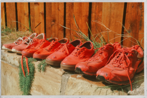 4 pairs of Red Shoes in row on a stone wall