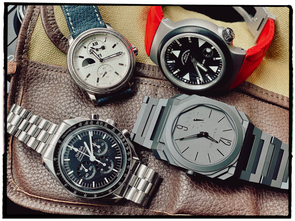 Four watches laying on a leather and canvas watch roll