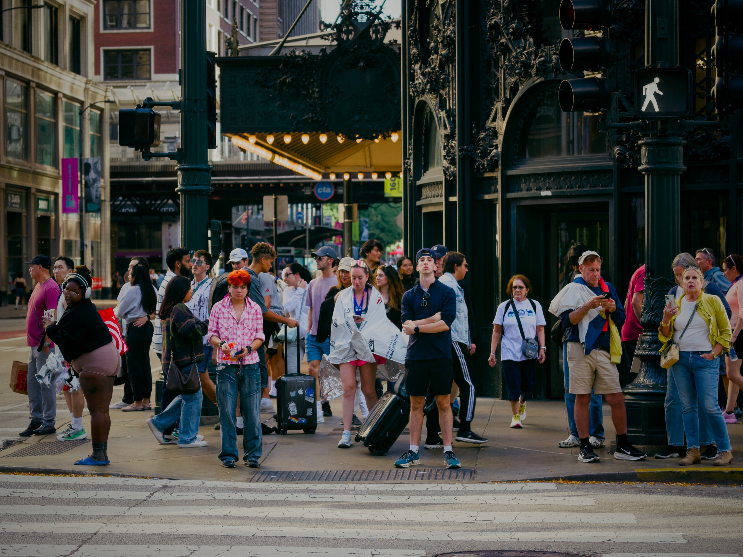 Group of people standing at the crosswalk wait for the signal to change in downtown Chicago